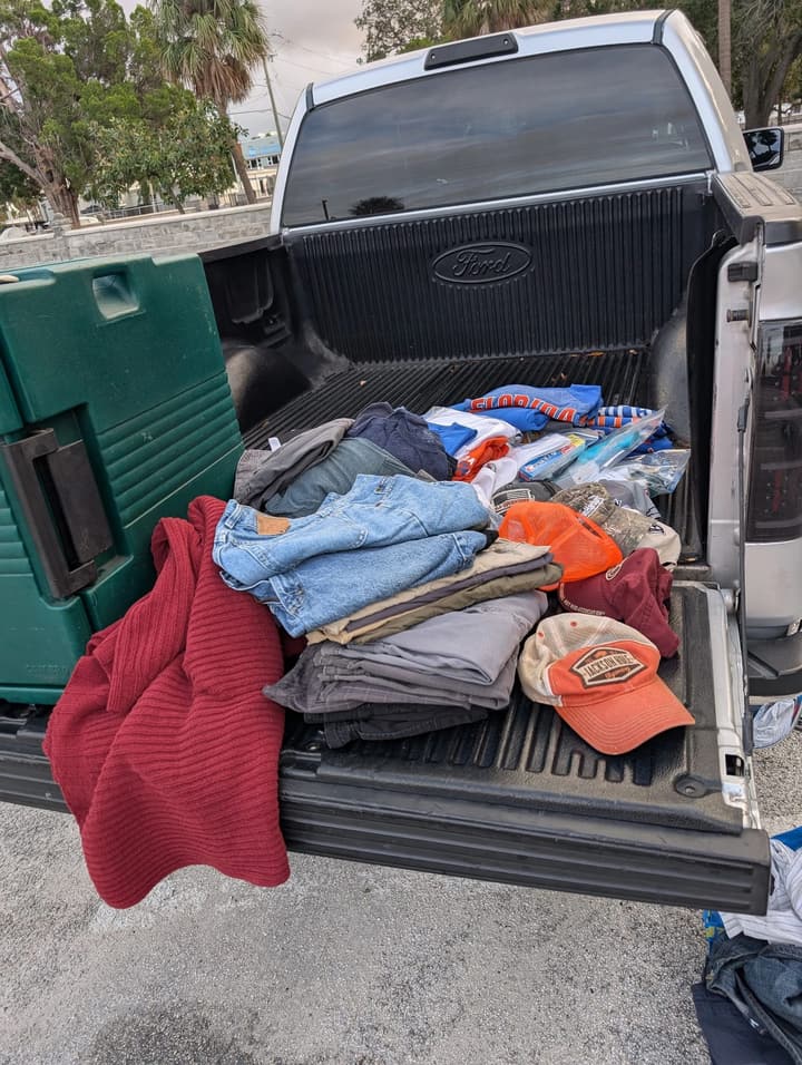 Donated jeans, sweaters, ball caps and toiletries laid out on a pickup truck's tailgate