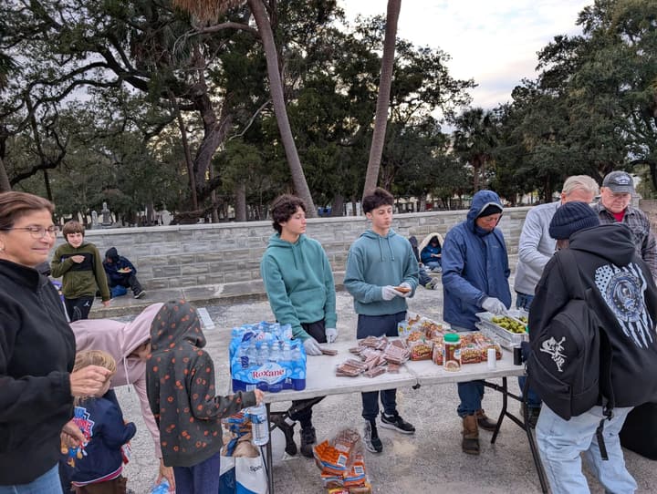Young volunteers in gloves hand out snack cakes and bottled water as people come through the line