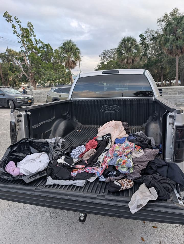 Donated clothing piled in the bed of a pickup truck, ready to give away