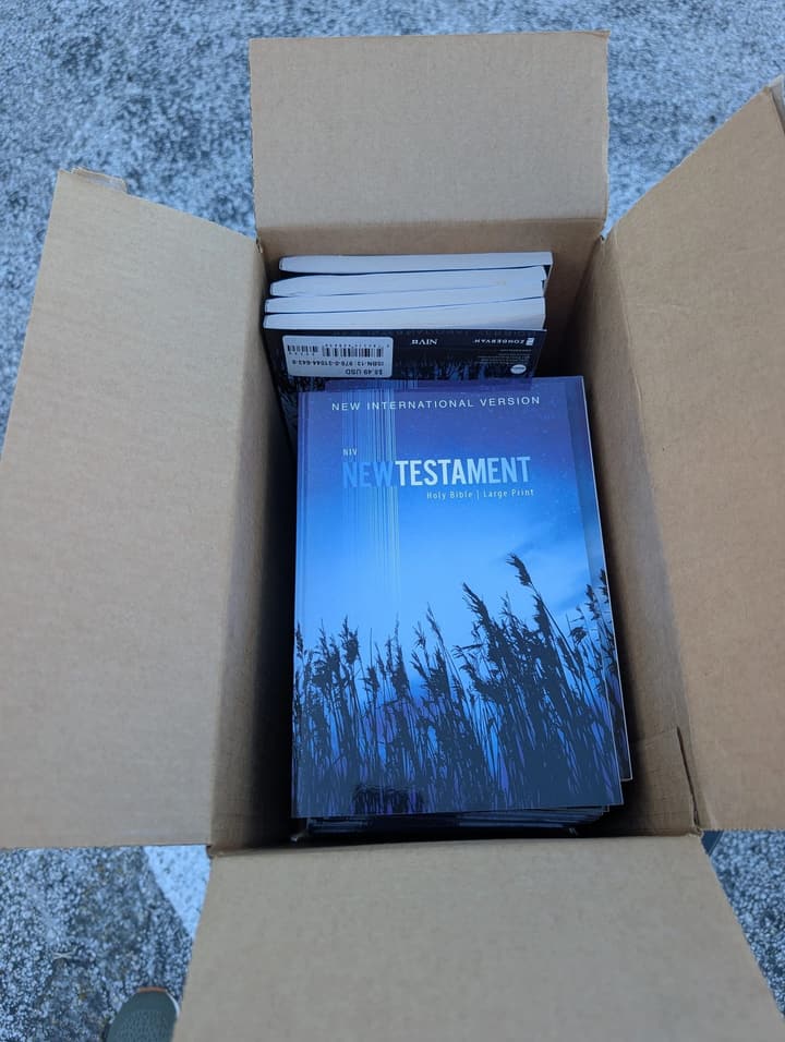 An open box of large-print New Testaments ready to give away