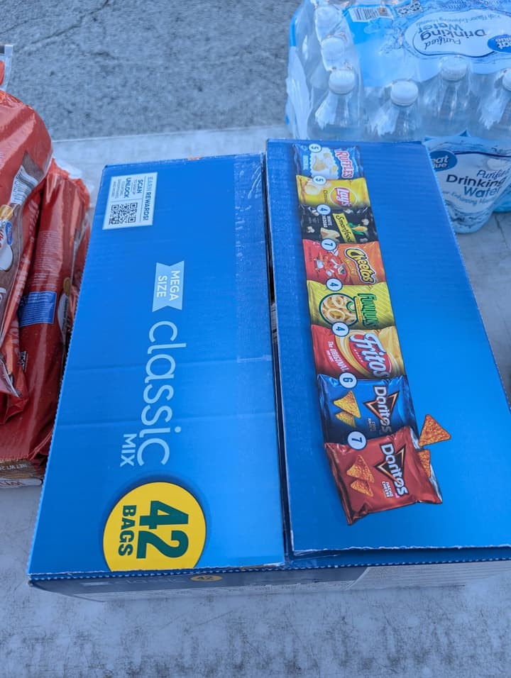 A 42-bag variety box of chips beside cases of bottled water on the serving table