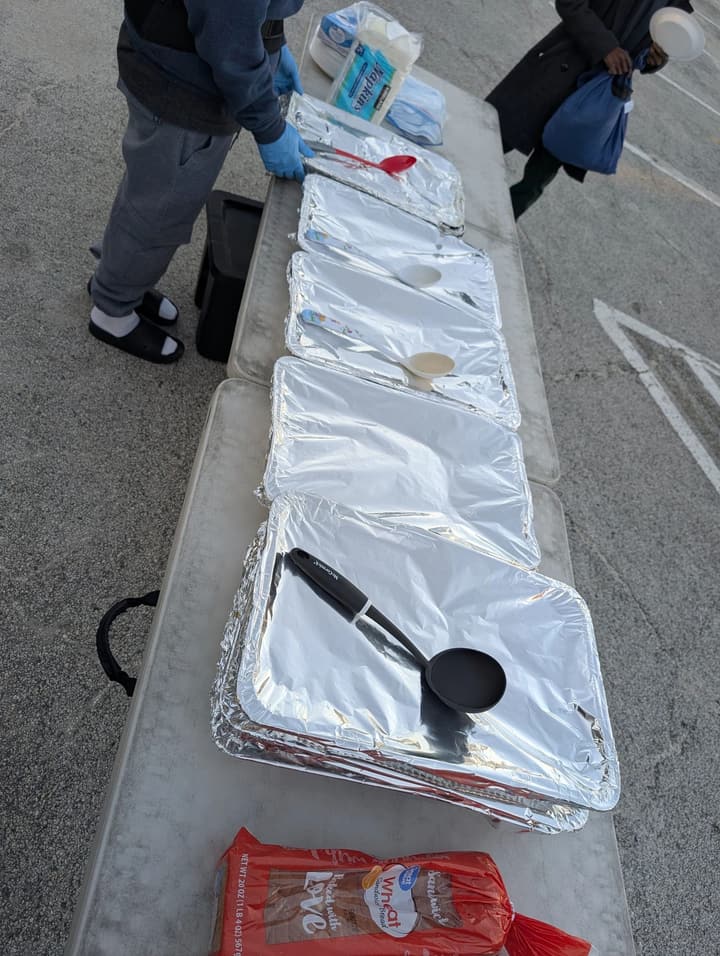 A row of foil-covered pans of hot food with serving spoons lined up on the table