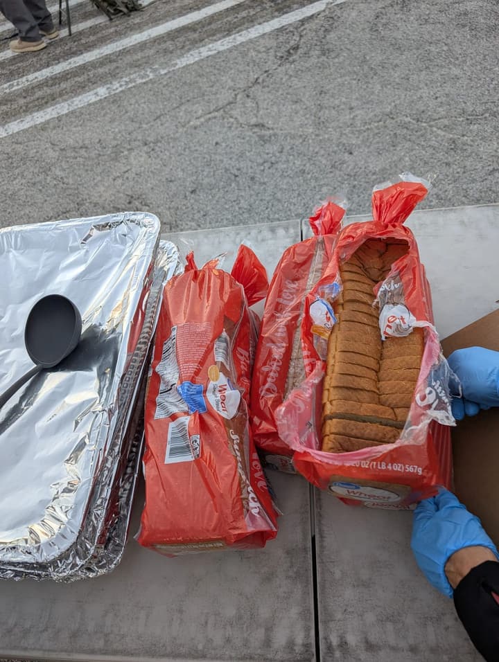 Open loaves of bread set out beside a foil pan and ladle on the serving table