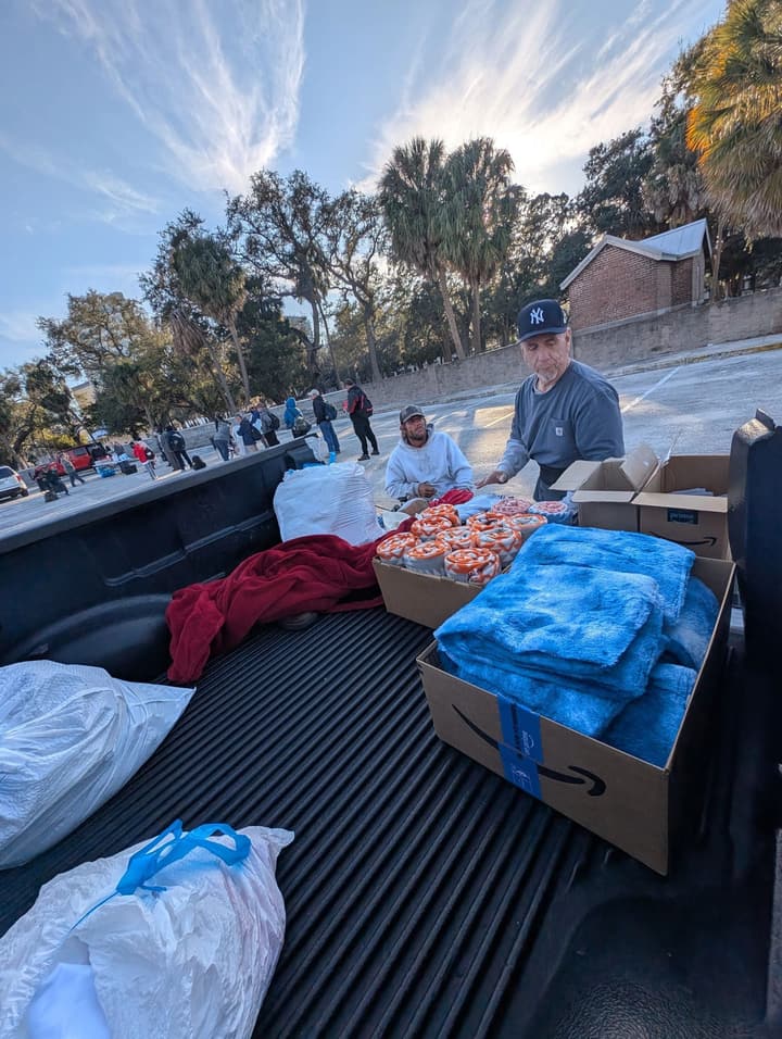Volunteers hand out donated blankets and supplies from the back of a pickup truck