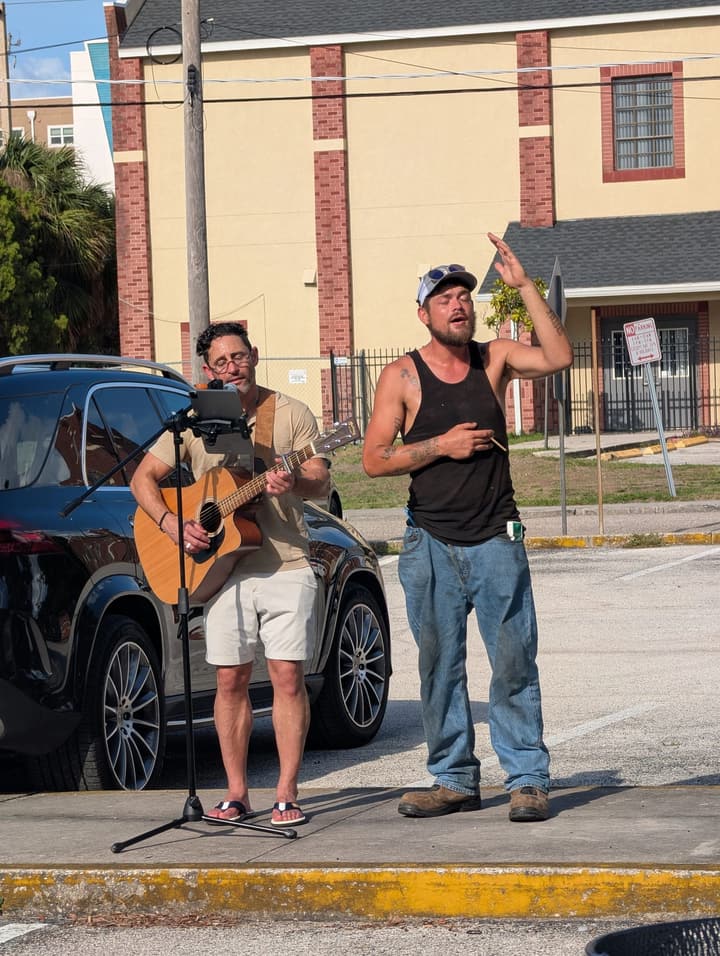 A guitarist plays as another man sings with a raised hand during the meal